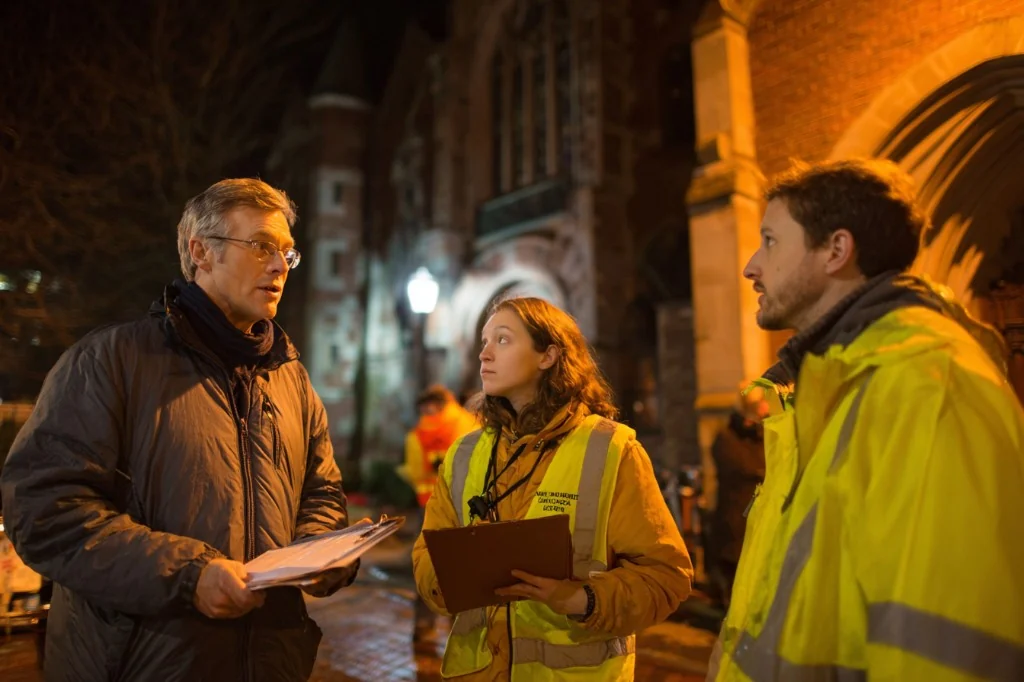 Volunteer safety leads debriefing with clipboards outside a brick church building at night
